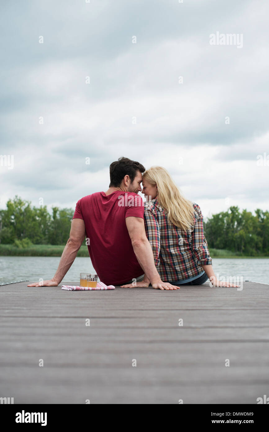 Un uomo e una donna seduta su un molo da un lago. Foto Stock
