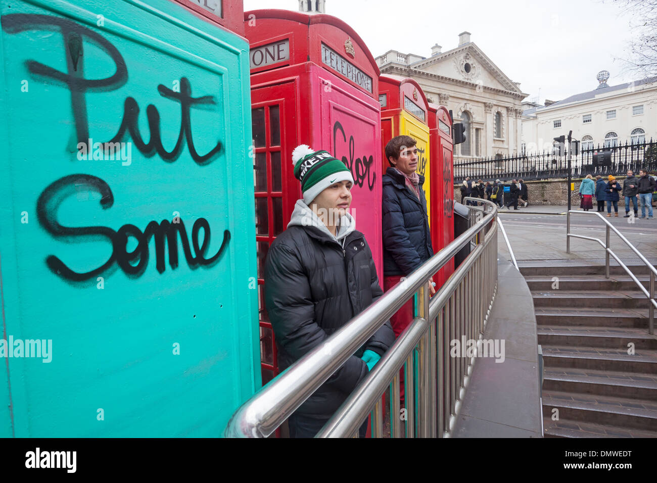 Londra, Charing Cross turisti in posa per le fotografie di fronte graffiti-coperta delle cabine telefoniche Foto Stock