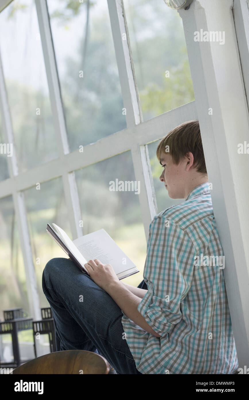 Un giovane persona seduta a leggere un libro. Foto Stock