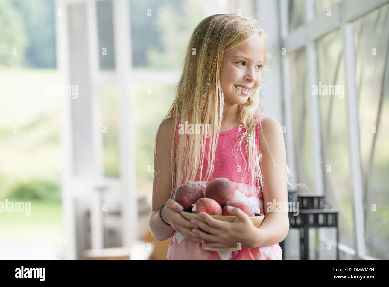 Una giovane ragazza con una bracciata di pesche fresche. Foto Stock