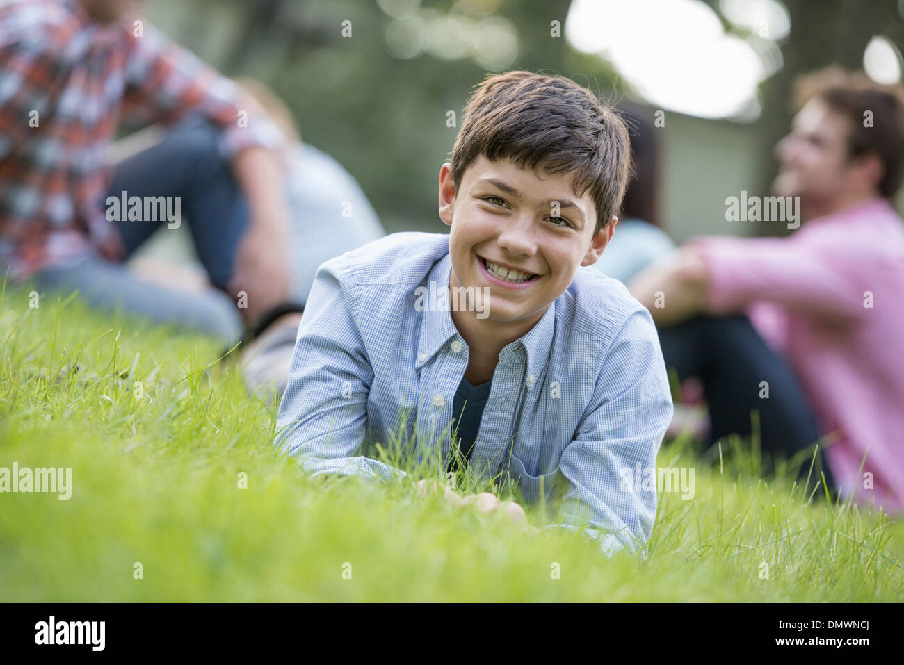 Un ragazzo seduto su erba a una festa estiva. Foto Stock