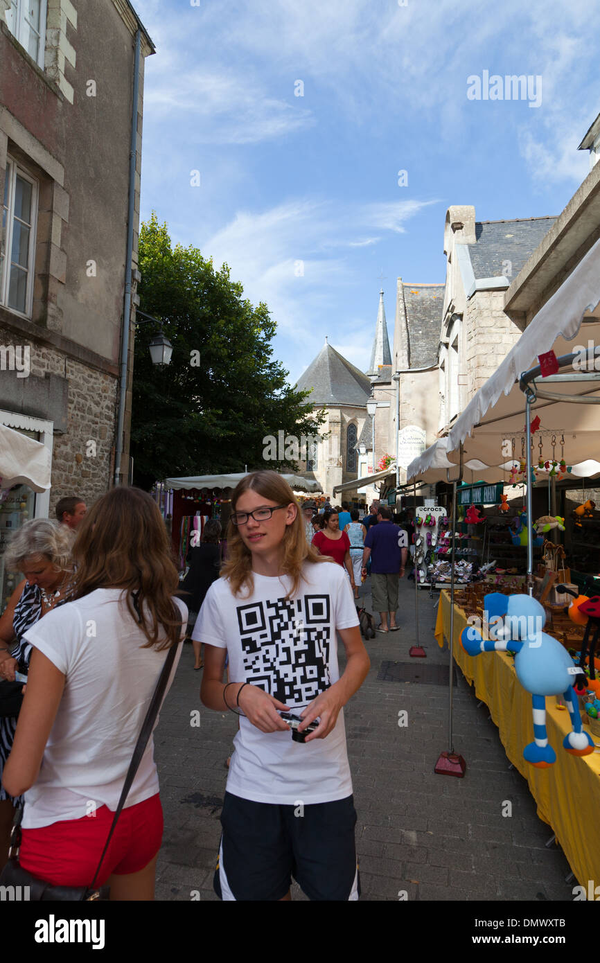Guerande mercato, con bancarelle e gli acquirenti con un giovane uomo che indossa tee shirt con il codice QR stampati su di essa Foto Stock