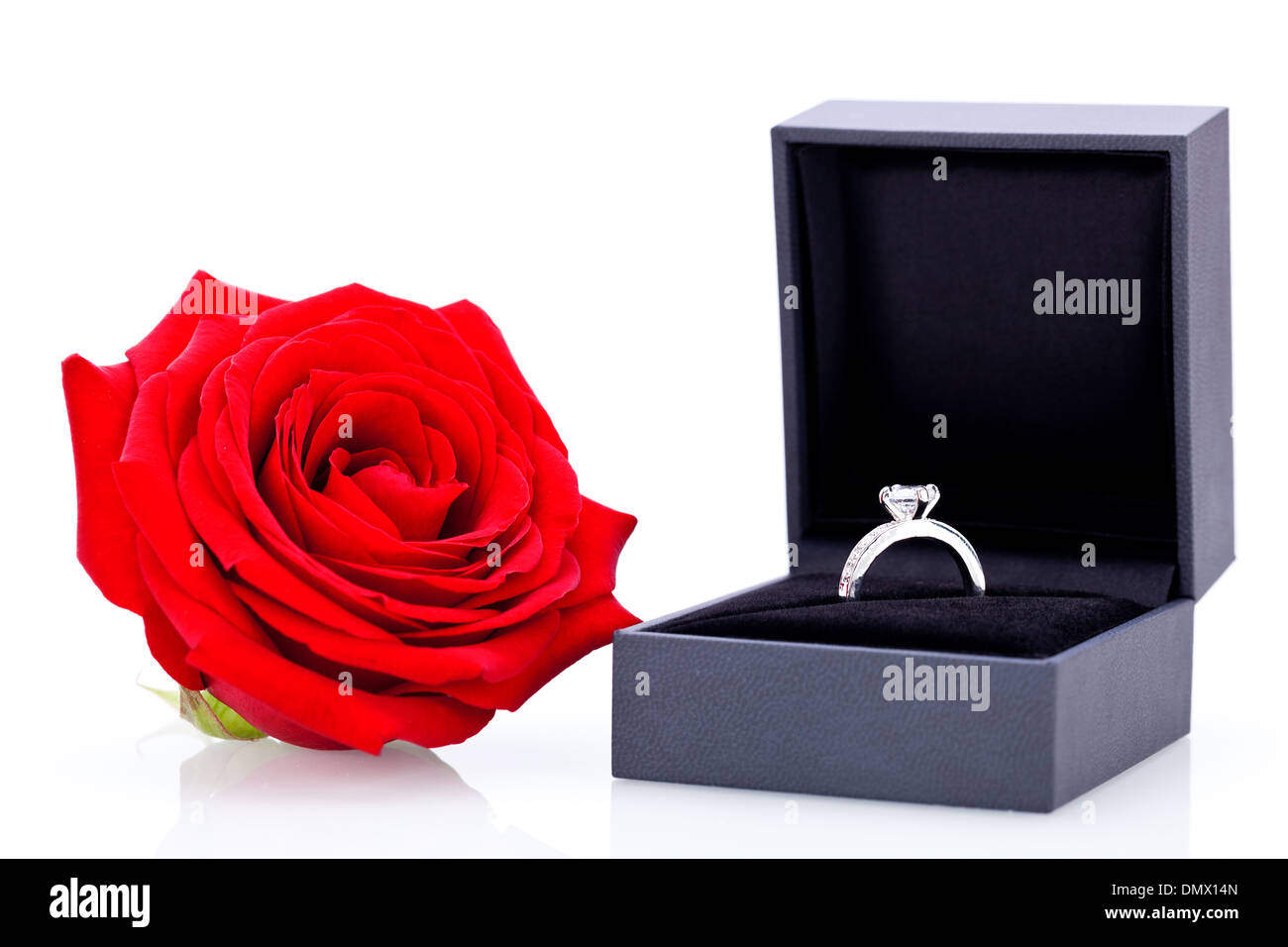 Anello di fidanzamento o regalo di San Valentino per una fidanzata con un mazzo di rose rosse indicano amore immortale su sfondo bianco Foto Stock