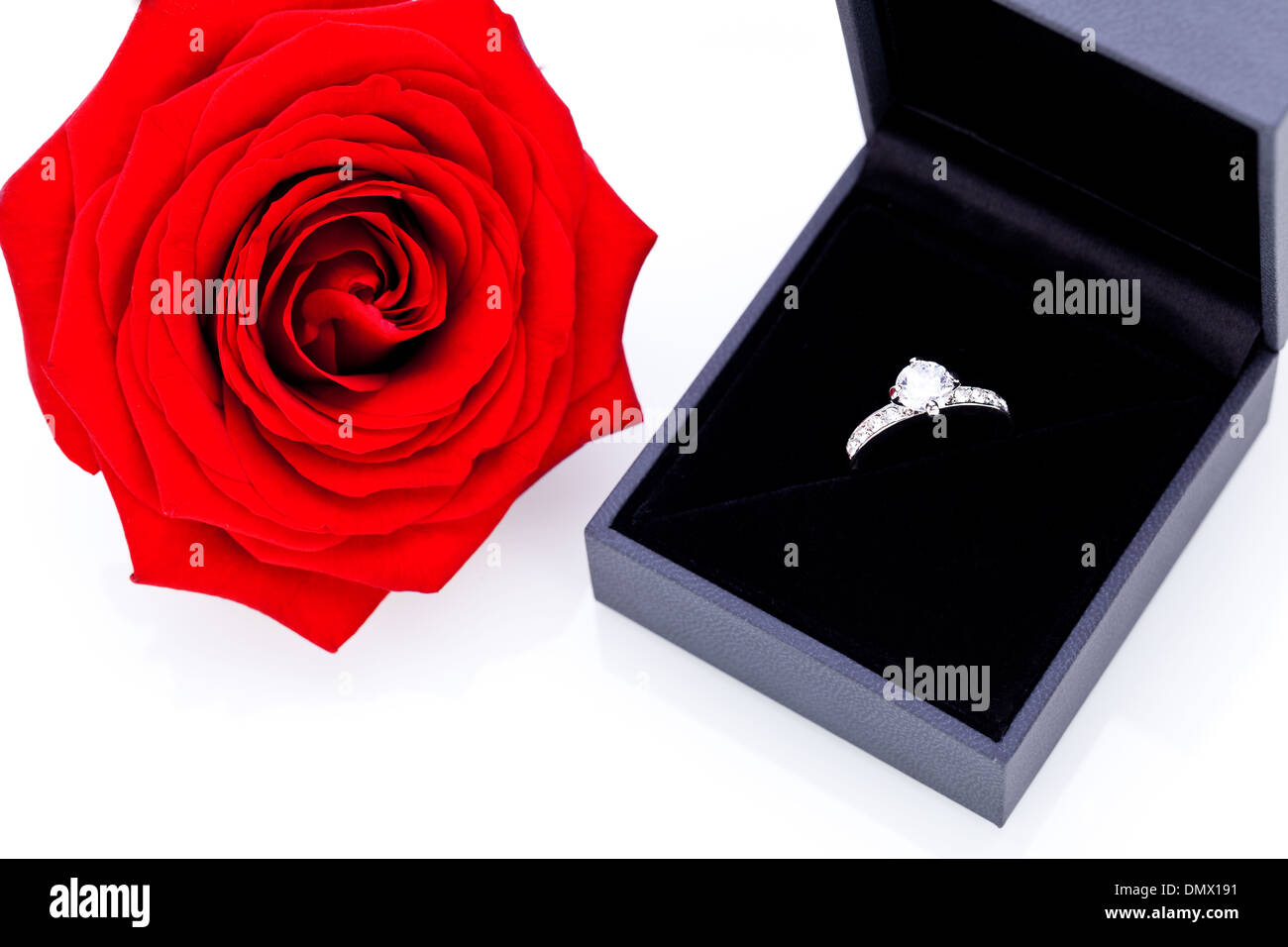 Anello di fidanzamento o regalo di San Valentino per una fidanzata con un mazzo di rose rosse indicano amore immortale su sfondo bianco Foto Stock