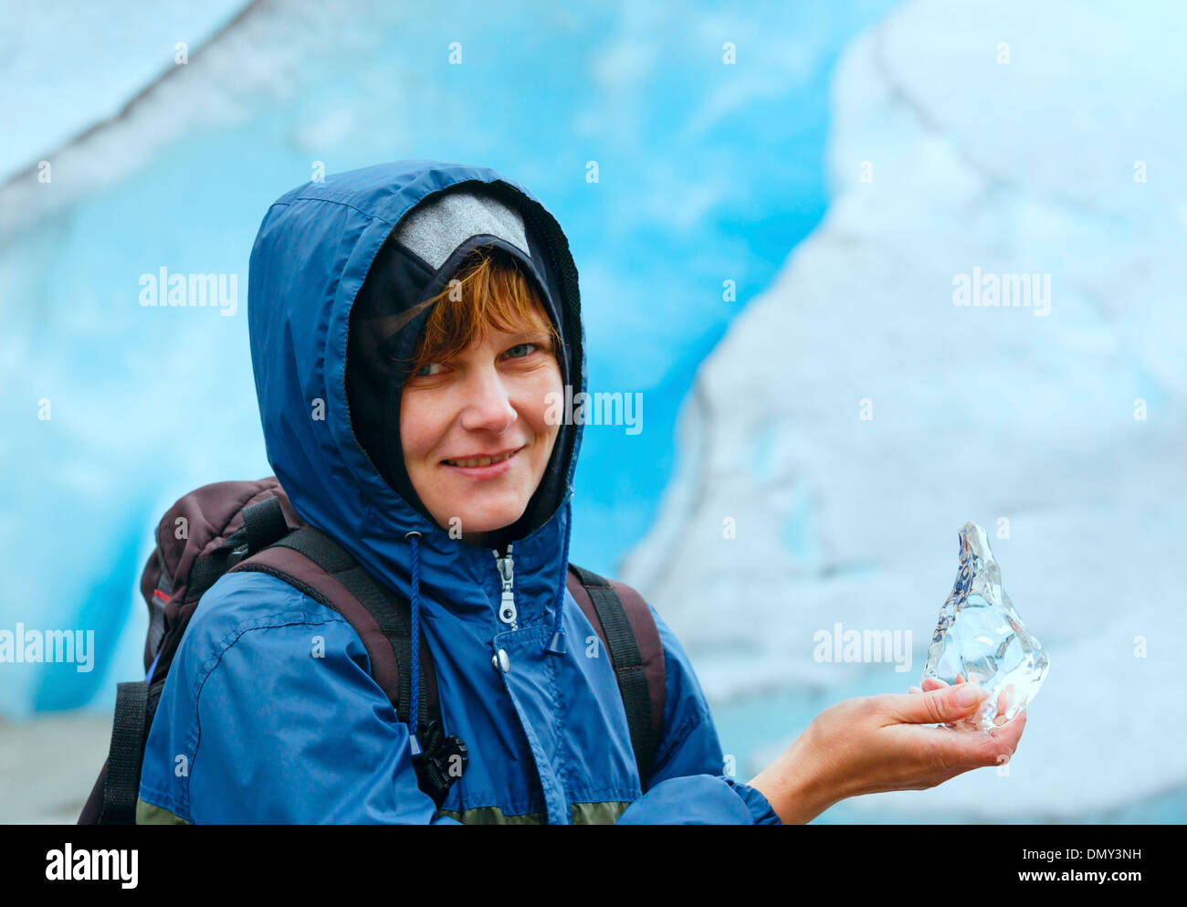 Ritratto di donna felice con un pezzo di ghiaccio in mano sul ghiacciaio Nigardsbreen sfondo (Norvegia) Foto Stock
