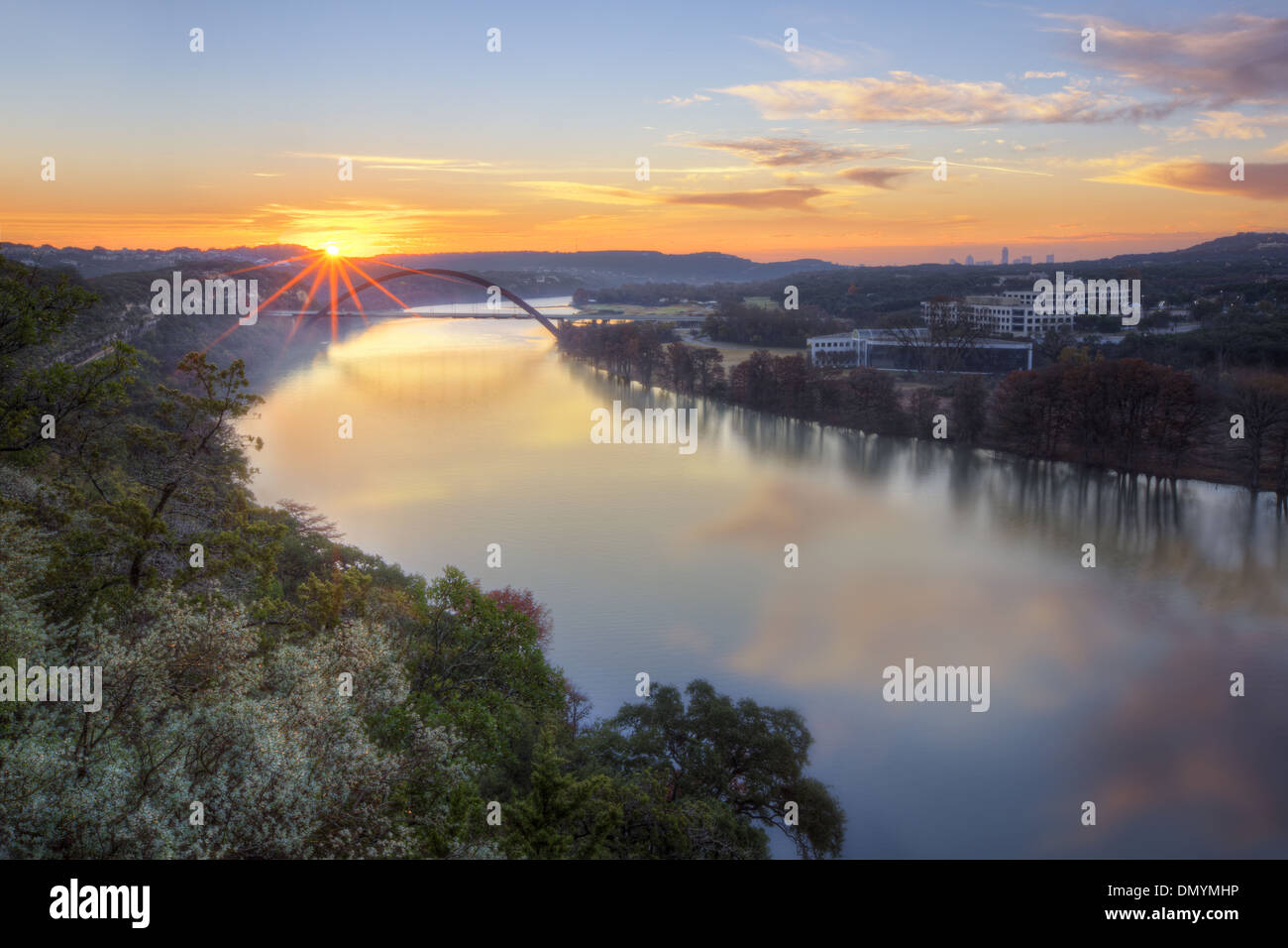 Il sole sorge sopra il fiume Colorado e Pennybacker Bridge. La distanza è la skyline di Austin. Foto Stock