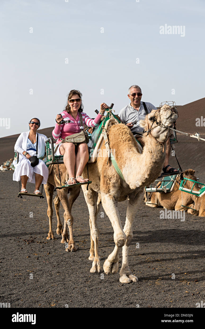 Felici i turisti in giro in cammello, Timanfaya, Lanzarote, Isole Canarie, Spagna Foto Stock