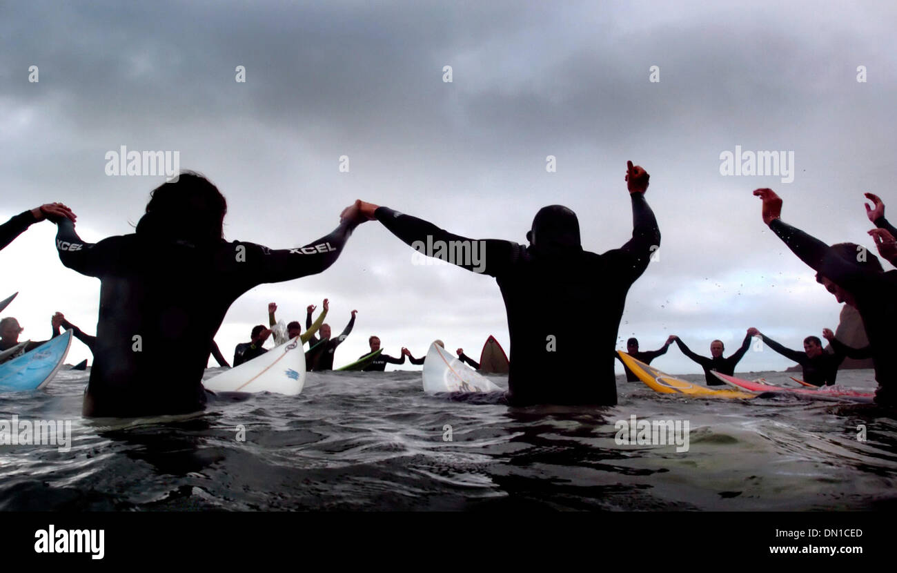 Feb 07, 2006; Half Moon Bay, CA, Stati Uniti d'America; Surfers unire le mani in un momento di silenzio mentre la benedizione le onde a mezzo miglio fuori nell'Oceano Pacifico a non conformisti spiaggia di Half Moon Bay. Il simbolico mostra di rispetto è una tradizione dando dei calci fuori alla cerimonia di apertura del Mavericks Surf Contest. Credito: foto di Kevin tedesco/Sacramento Bee/ZUMA premere. (©) Copyright 2006 by Sacram Foto Stock
