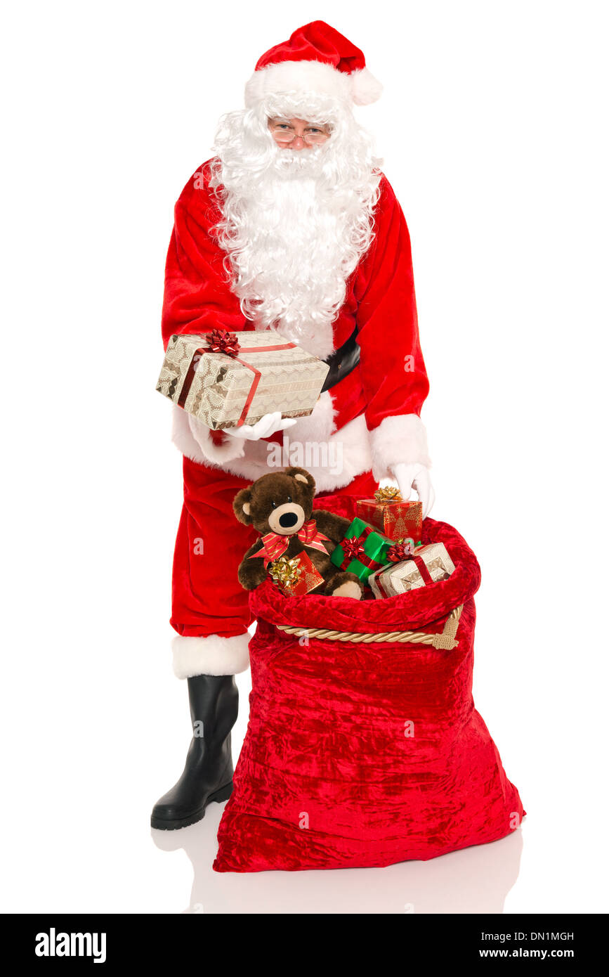 Santa Claus o Babbo Natale consegna un regalo dal suo sacco pieno di giocattoli, isolato su uno sfondo bianco. Foto Stock