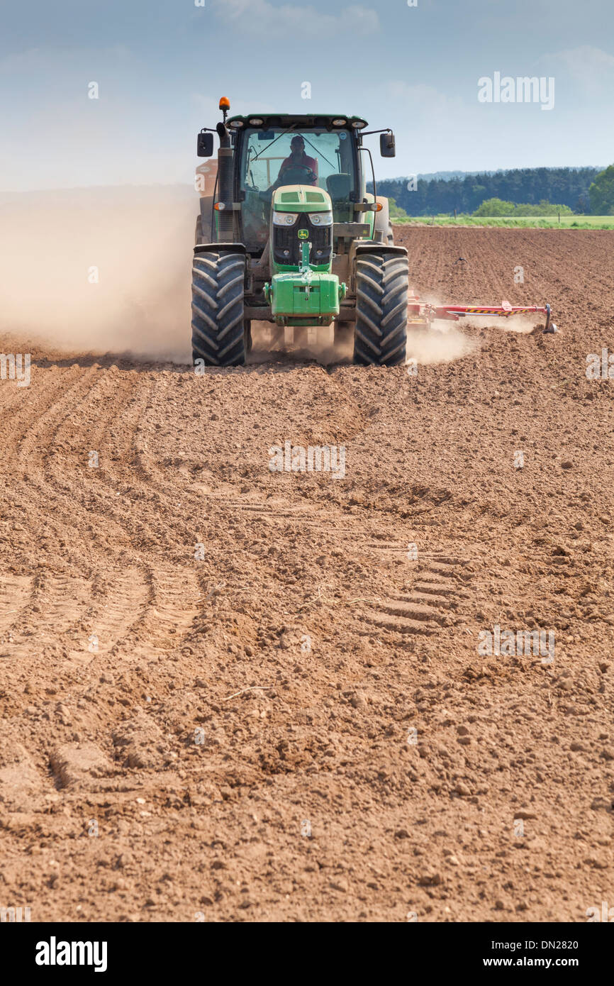 Terreno polveroso vola da ruote e attrezzature come un trattore trapani seme in un campo. Foto Stock