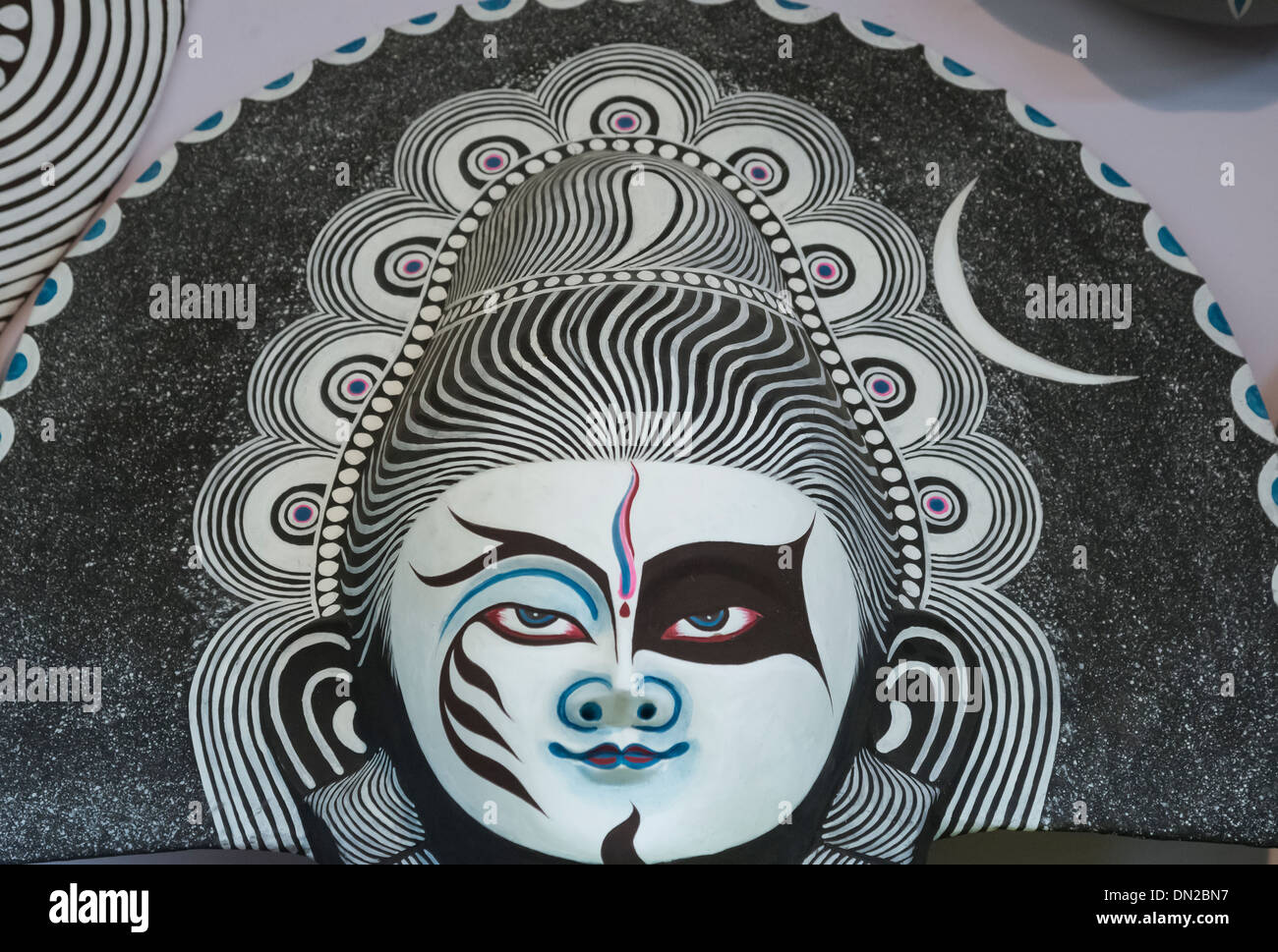 La lavorazione artigianale della maschera di carta del signore Shiva nei colori del bianco e del nero,blu, rosa che indica varie qualità di Dio. Foto Stock