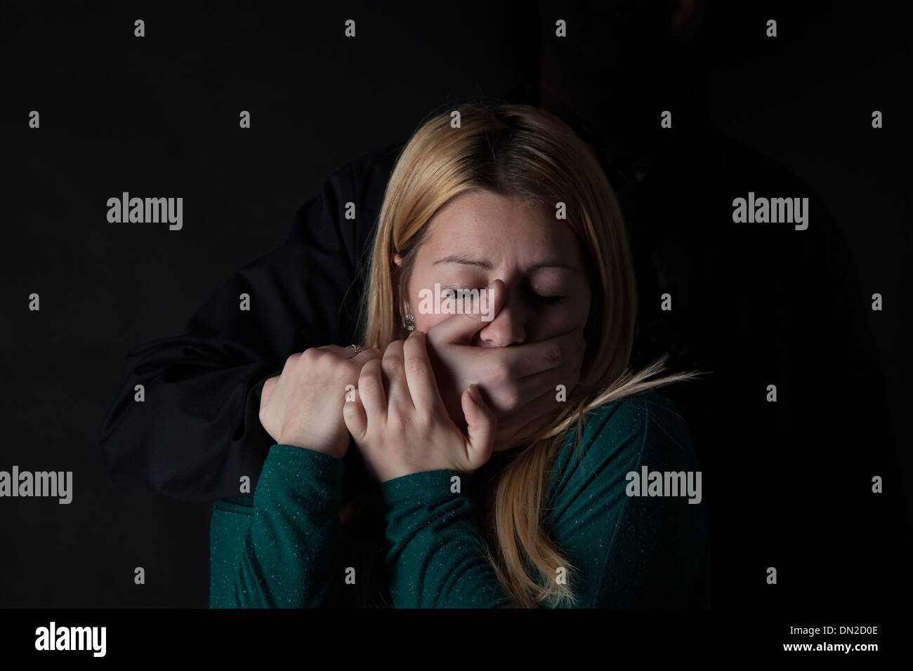 Giovane donna con la mano che copre la bocca da dietro. Foto Stock