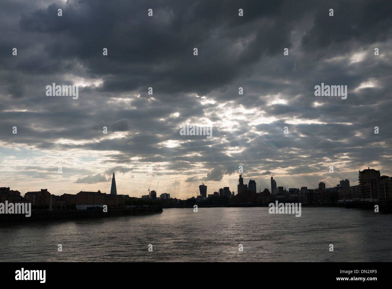 Rompendo la luce del sole attraverso le nuvole sopra il fiume il Tamigi e lo skyline della città da est di Londra, Regno Unito. Foto Stock