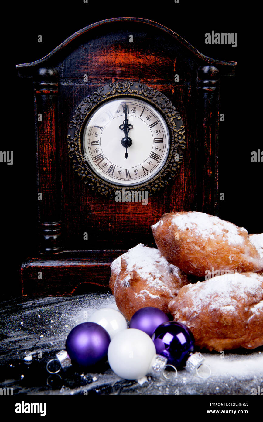 Ciambella olandese noto anche come oliebollen, tradizionale di Capodanno cibo, orologio sulla mezzanotte su sfondo nero Foto Stock