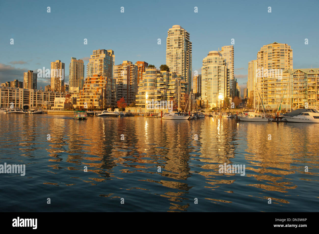 La riflessione di Yaletown edifici appartamento al tramonto attraverso False Creek da Granville Island, Vancouver BC Canada Foto Stock