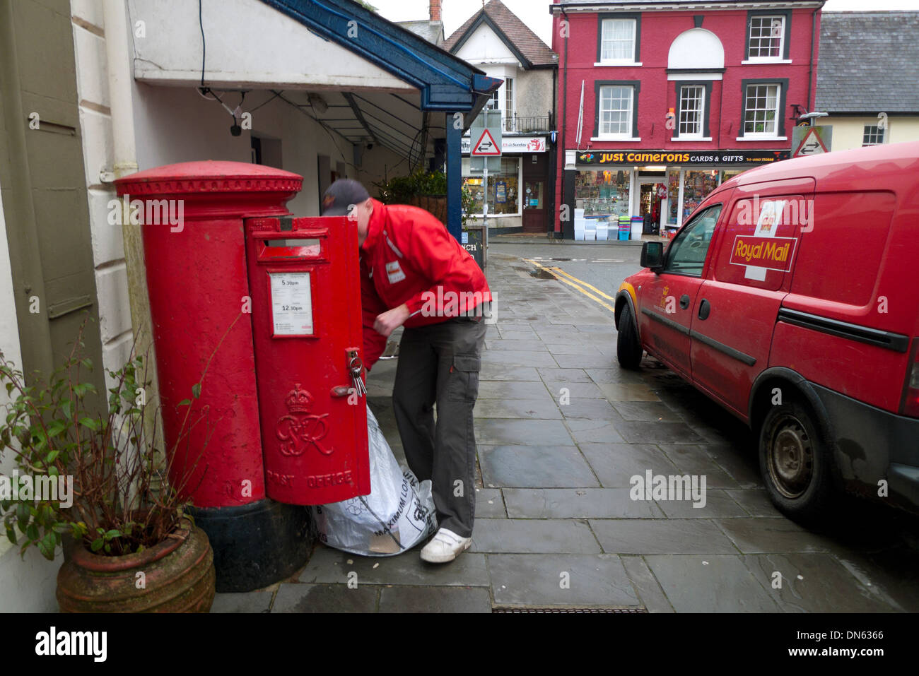 Un lavoratore postale posta di svuotamento in un sacco da un rosso casella postale accanto a un ufficio postale van Llandovery Wales UK KATHY DEWITT Foto Stock