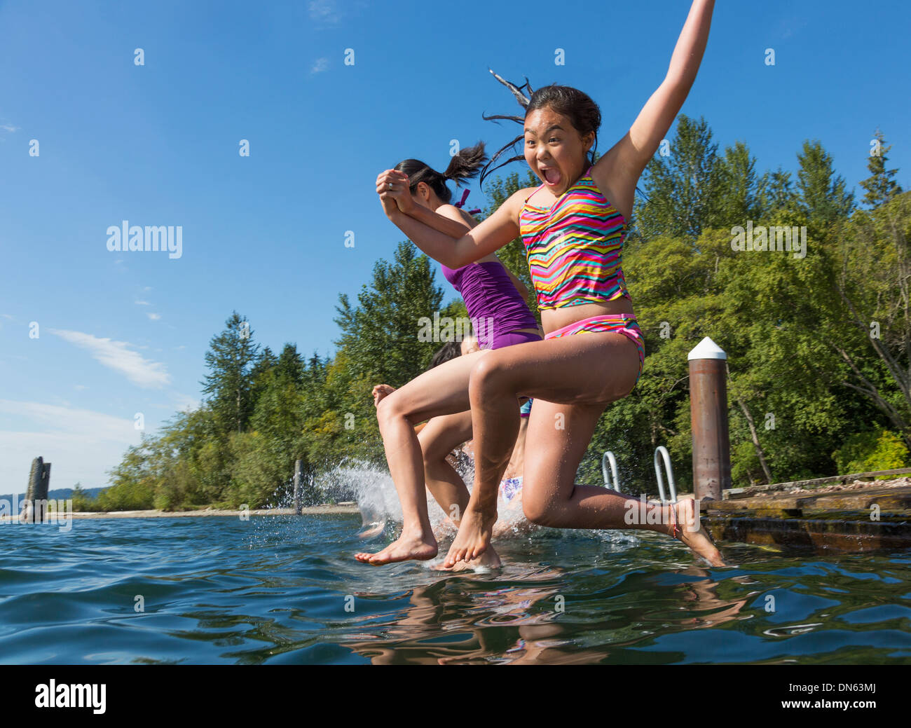 Ragazze jumping insieme nel lago Foto Stock