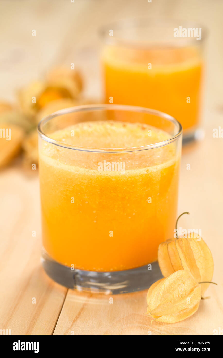 Preparate di fresco succo fatto di physalis (lat. Physalis peruviana) servita in vetro con frutti physalis sul lato Foto Stock