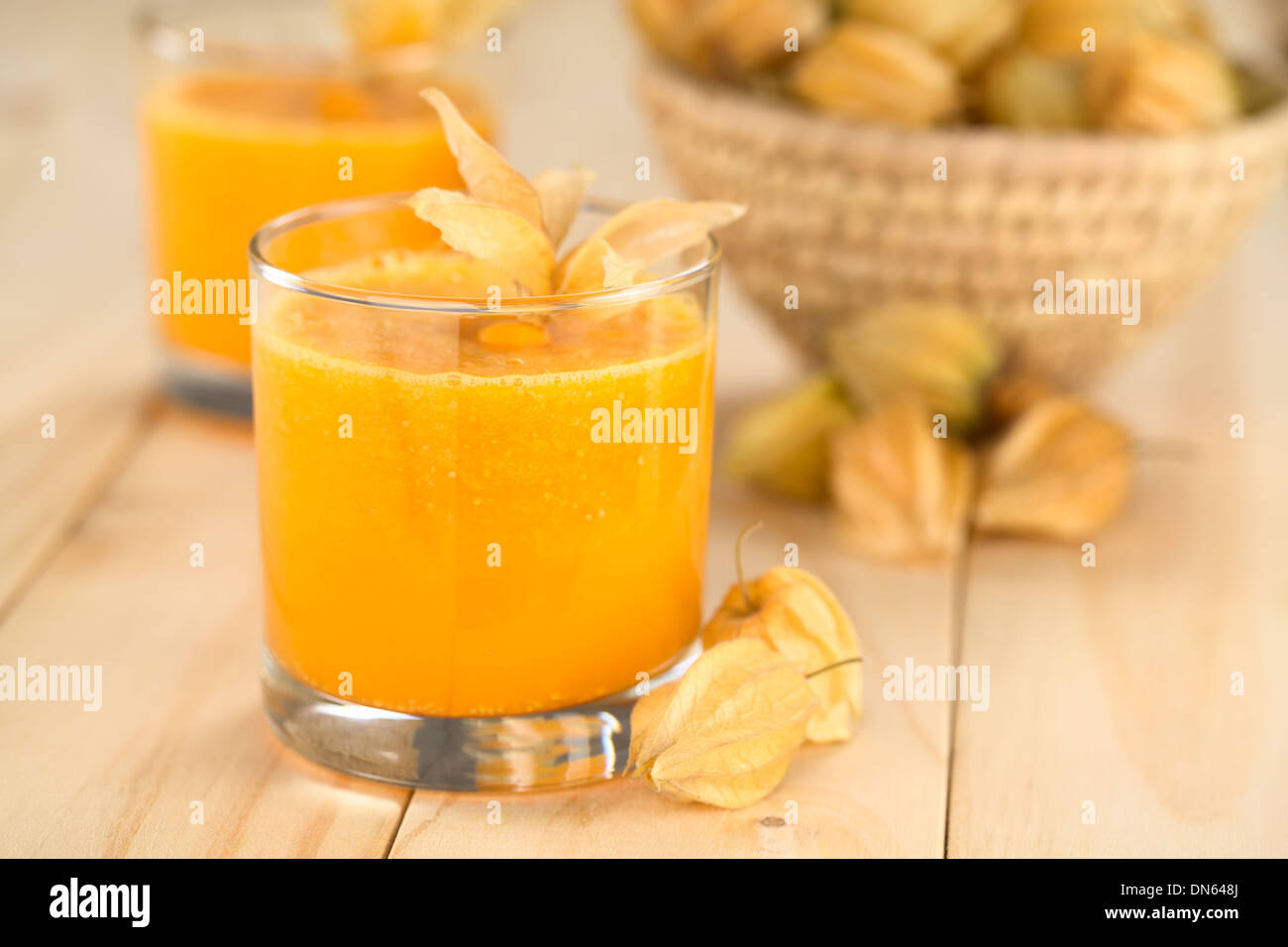 Preparate di fresco succo fatto di physalis (lat. Physalis peruviana) servita in vetro con frutti physalis sul lato Foto Stock