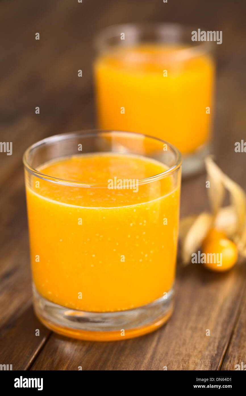 Preparate di fresco succo fatto di physalis (lat. Physalis peruviana) servita in vetro con frutti physalis sul lato Foto Stock