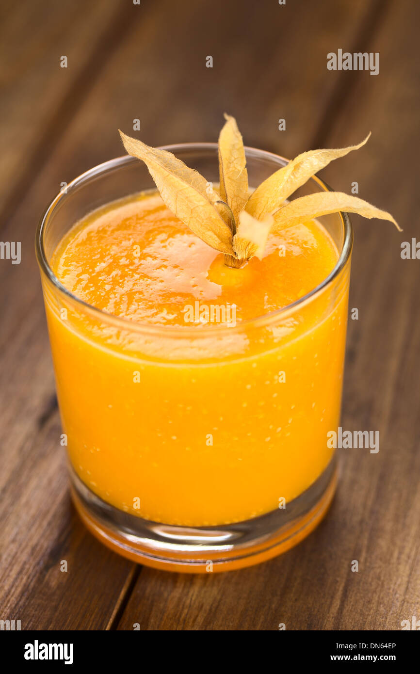 Preparate di fresco succo fatto di physalis (lat. Physalis peruviana) servita in bicchiere guarnito con un physalis Foto Stock
