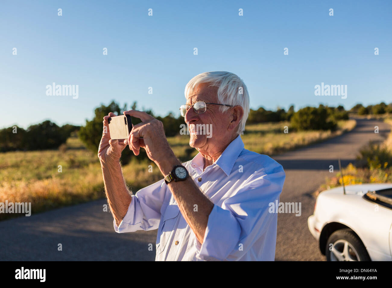 Senior uomo caucasico di scattare le foto con il telefono cellulare Foto Stock