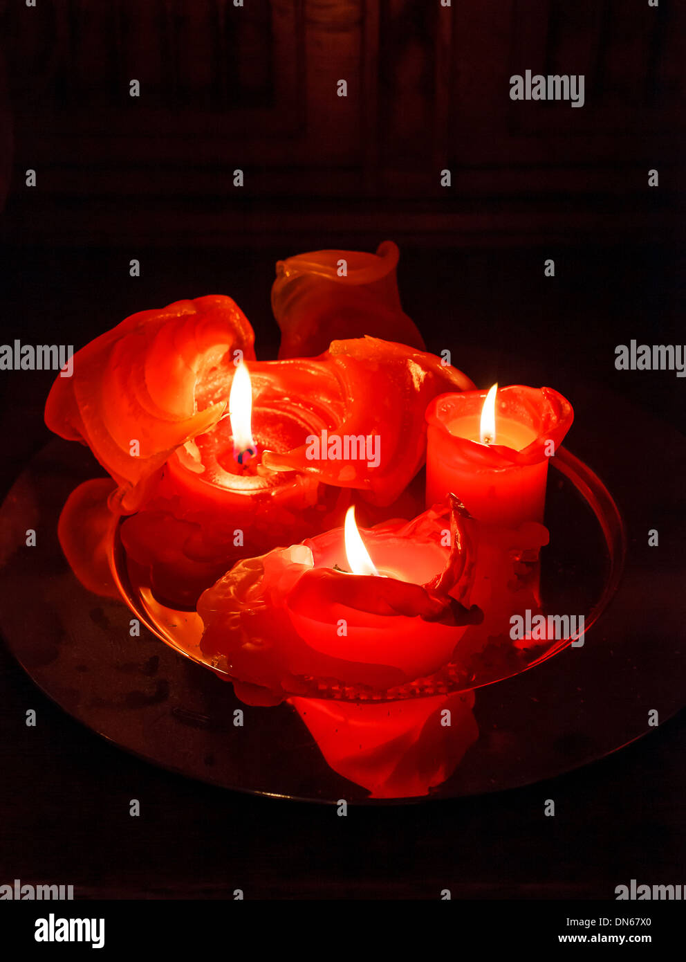 Tre rossi candele romantiche sulla piastra di notte Foto stock - Alamy