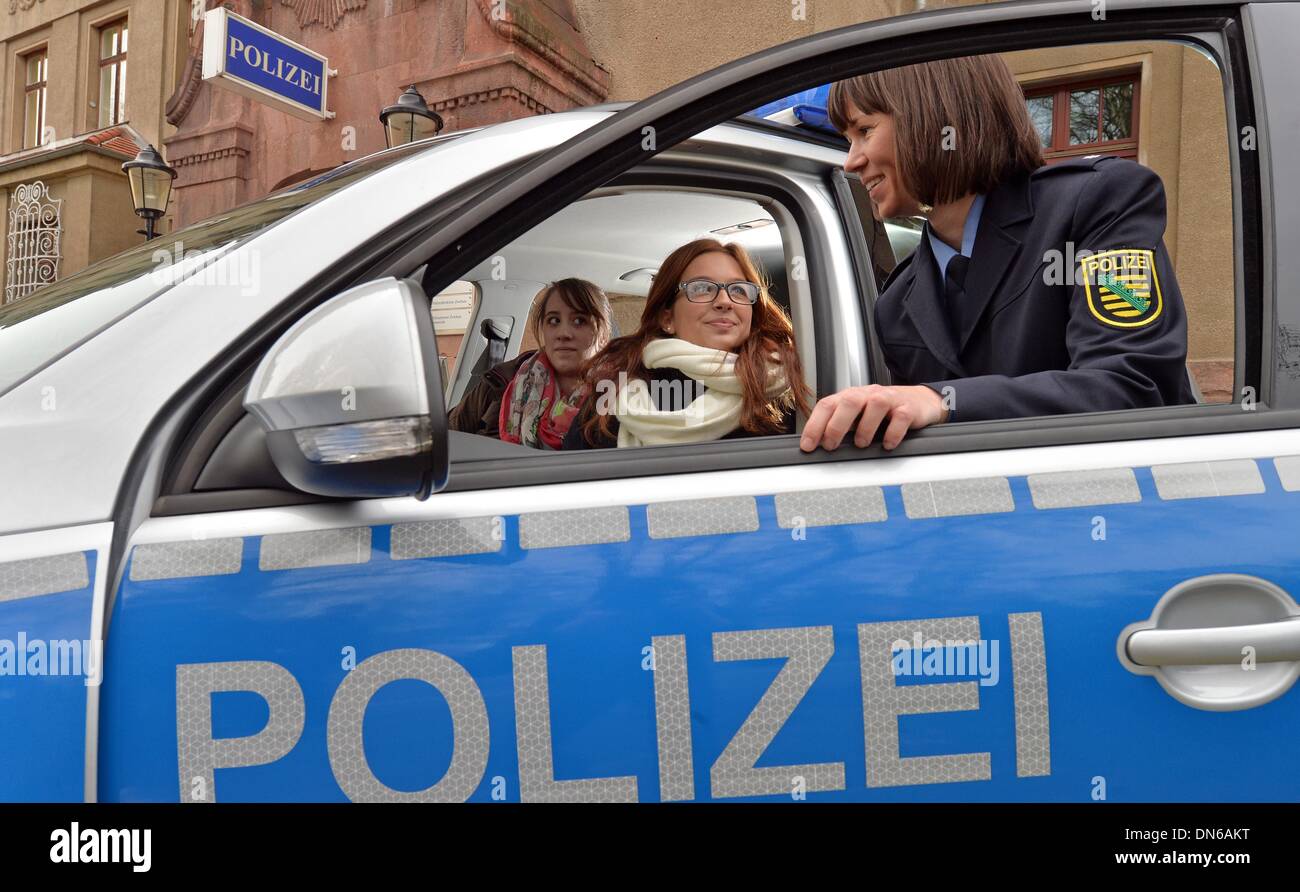 Zwickau, Germania. Xix Dec, 2013. Il commissario di polizia di Katharina Matt colloqui con gli alunni Michelle Poetzl (L) e Vanessa Hlawaty nella parte anteriore di una macchina della polizia in Zwickau, Germania, 19 dicembre 2013. Il prossimo anno gli studenti hanno la possibilità di assolvere un 10-giorni-stage presso la polizia. Foto: Hendrik Schmidt/dpa/Alamy Live News Foto Stock