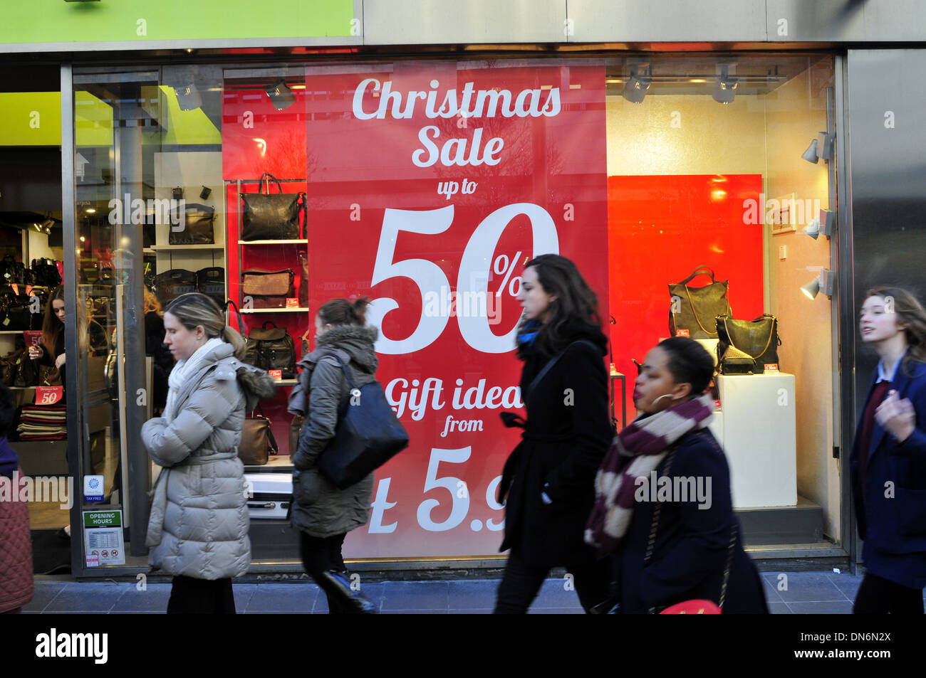 Le donne a piedi passato un negozio con un poster la lettura 'Natale vendita, fino al 50 per cento off' Foto Stock