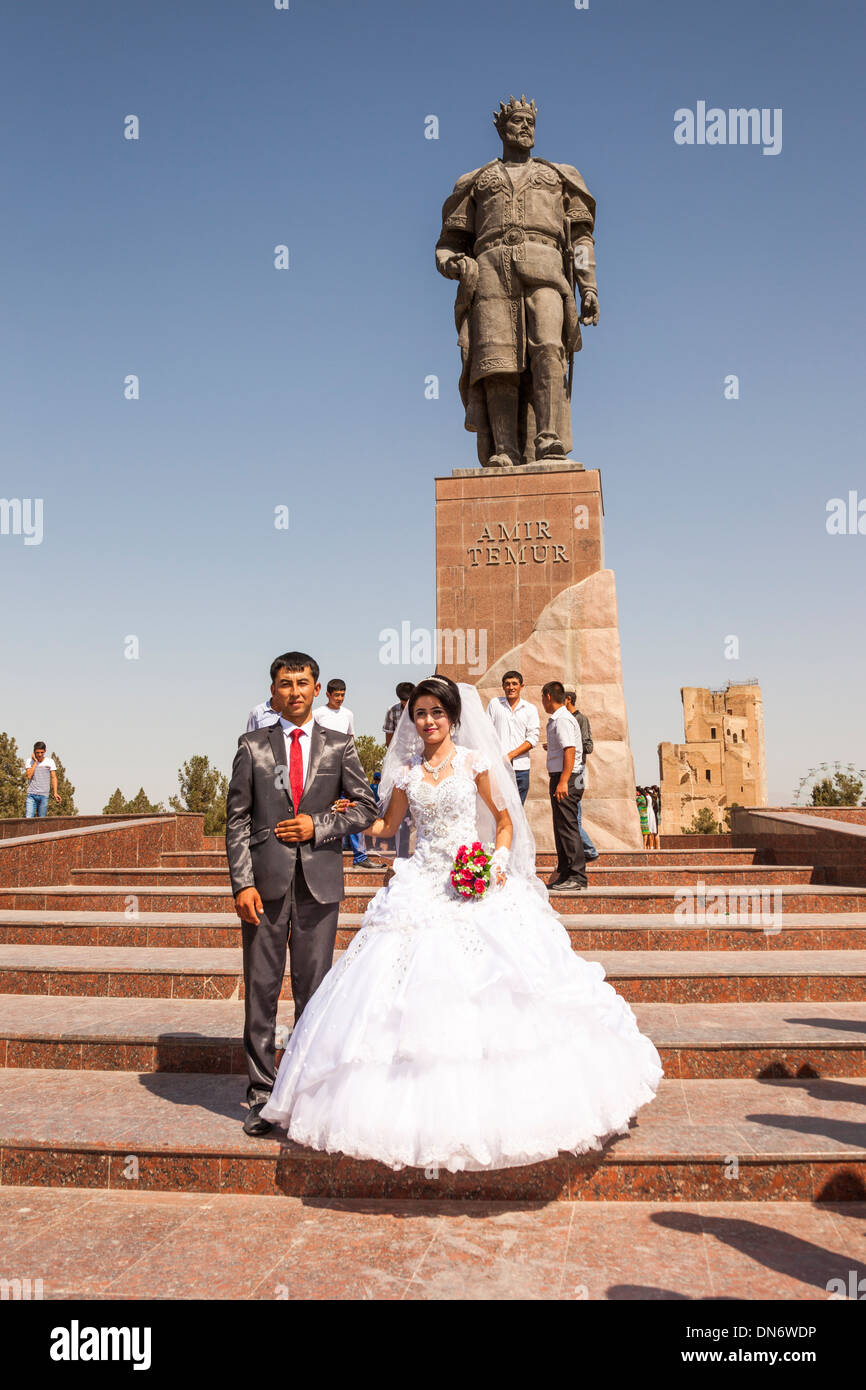 Sposa e lo sposo di fronte della statua di Amir Timur, noto anche come Temur e Tamerlane, Shakhrisabz, Uzbekistan Foto Stock