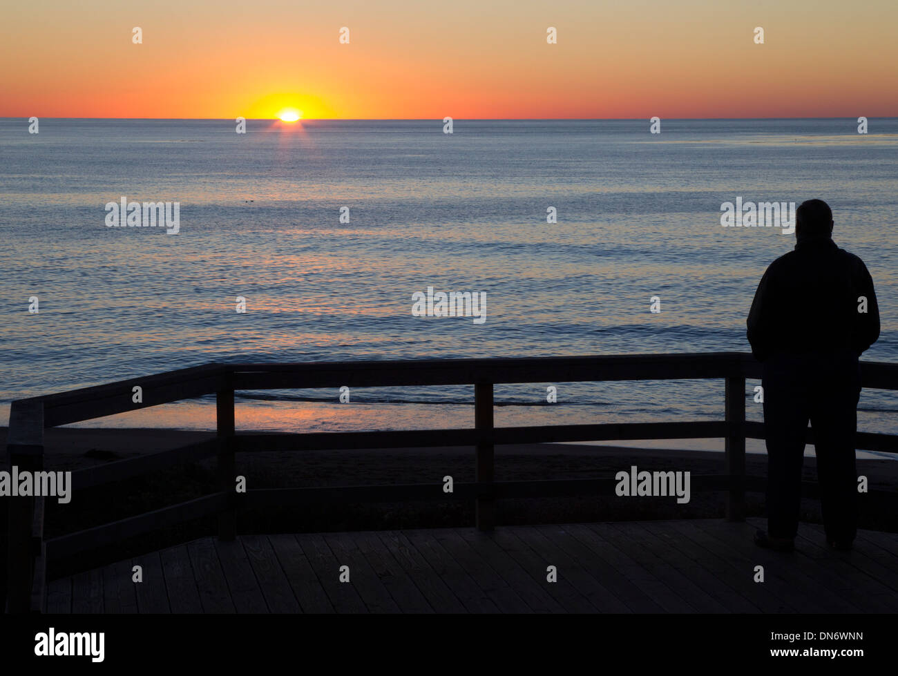 Uomo che guarda il tramonto sull'Oceano Pacifico Foto Stock