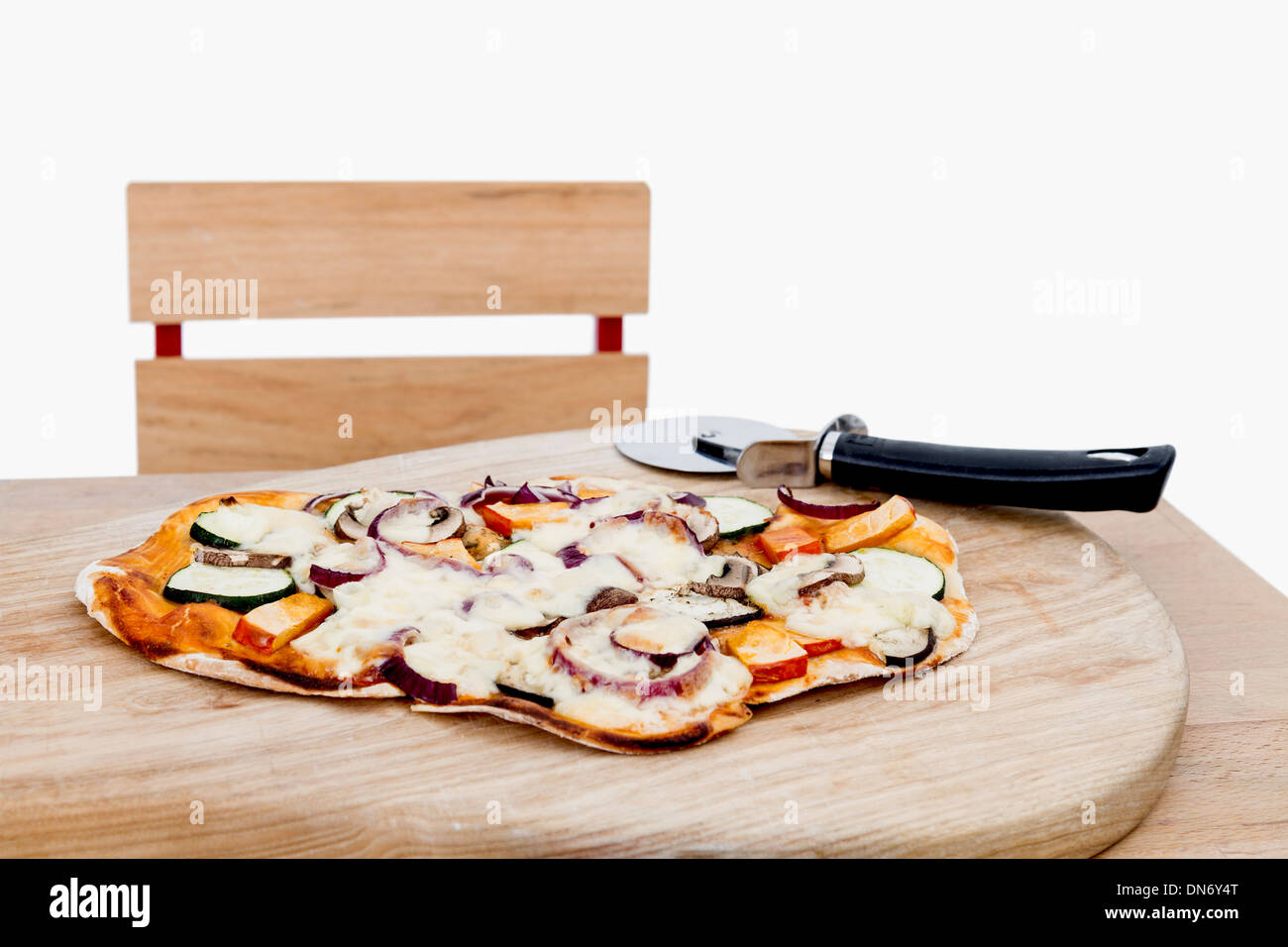 La pizza fatta in casa con taglierina sulla piccola scrivania in sfondo grigio chiaro Foto Stock