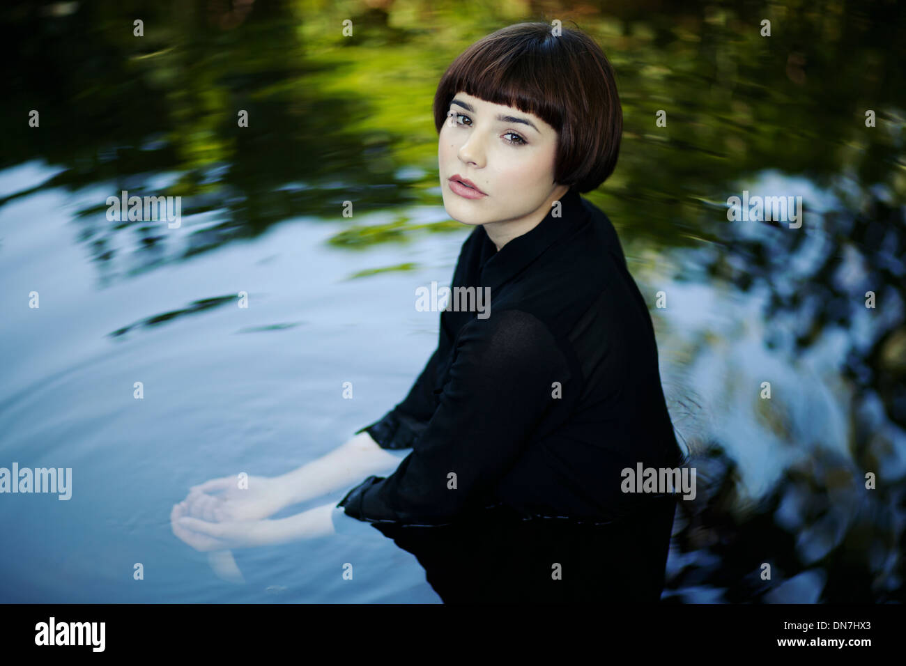 Giovane donna seduta in acqua, ritratto Foto Stock