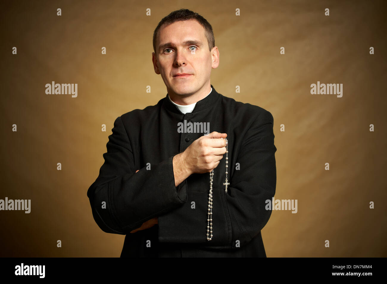 Giovane sacerdote con il rosario in mano Foto Stock