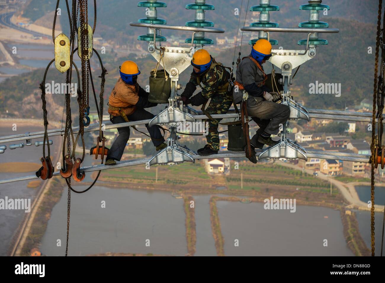 Zhoushan cinese della provincia dello Zhejiang. Xx Dec, 2013. Elettricisti opera su linee di trasmissione oltre 190 metri sopra il livello del suolo in Zhoushan, est della Cina di Provincia dello Zhejiang, Dic 19, 2013. La 500 kilovolt cross-mare di trasmissione di potenza di progetto è prevista da mettere in funzione dal gennaio 2014. Il 36,5 chilometri di progetto, di cui 8,39 chilometri si incontra il mare, è stata la più lunga del suo genere in Cina finora. © Xu Yu/Xinhua/Alamy Live News Foto Stock