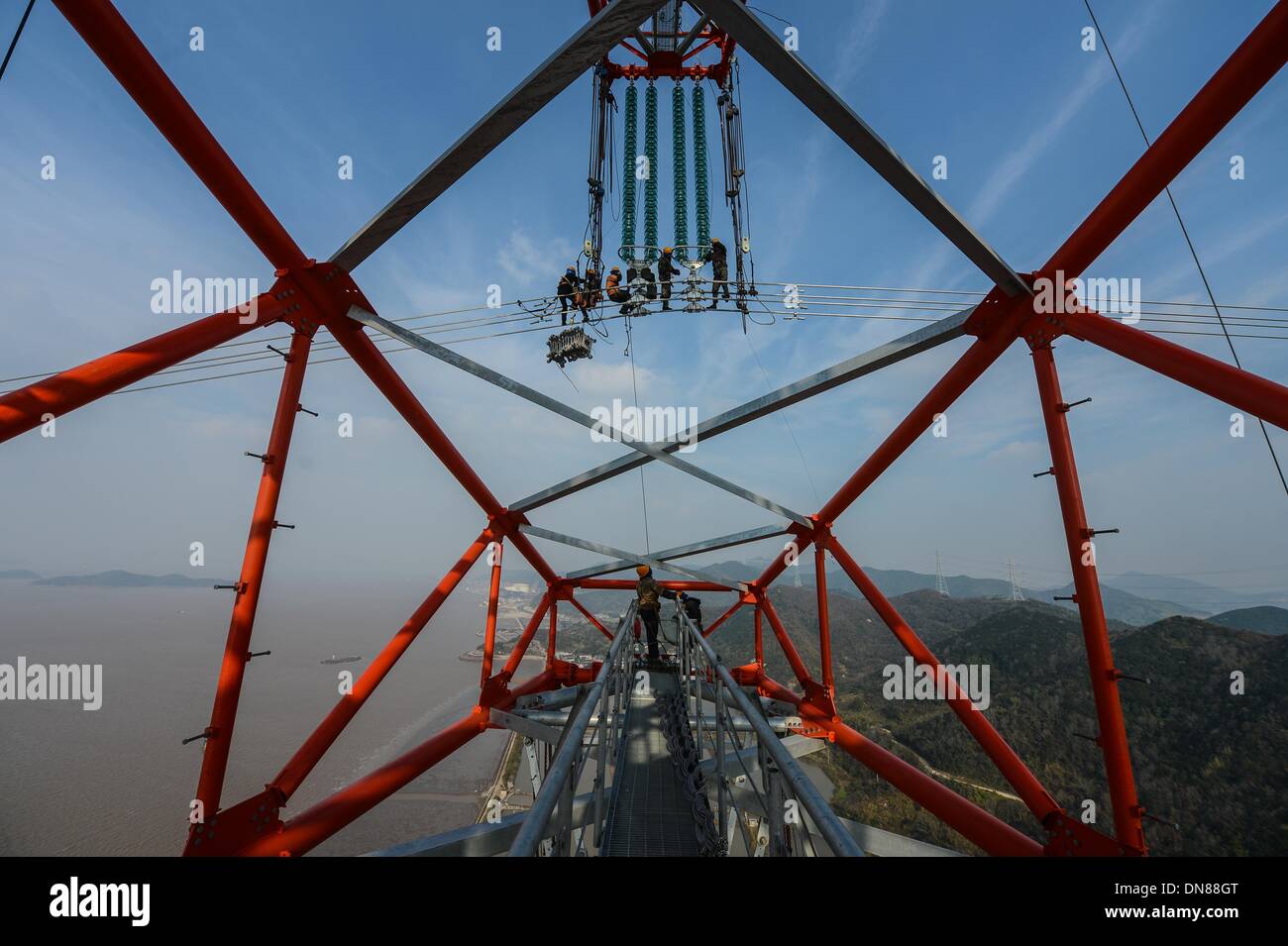 Zhoushan cinese della provincia dello Zhejiang. Xx Dec, 2013. Elettricisti opera su linee di trasmissione oltre 190 metri sopra il livello del suolo in Zhoushan, est della Cina di Provincia dello Zhejiang, Dic 19, 2013. La 500 kilovolt cross-mare di trasmissione di potenza di progetto è prevista da mettere in funzione dal gennaio 2014. Il 36,5 chilometri di progetto, di cui 8,39 chilometri si incontra il mare, è stata la più lunga del suo genere in Cina finora. © Xu Yu/Xinhua/Alamy Live News Foto Stock