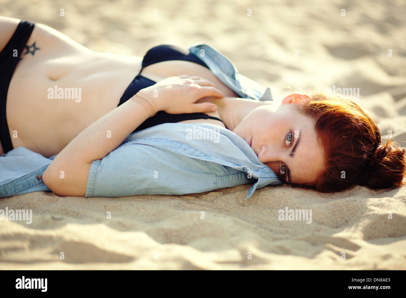 Giovane donna sdraiata sulla spiaggia, ritratto Foto Stock