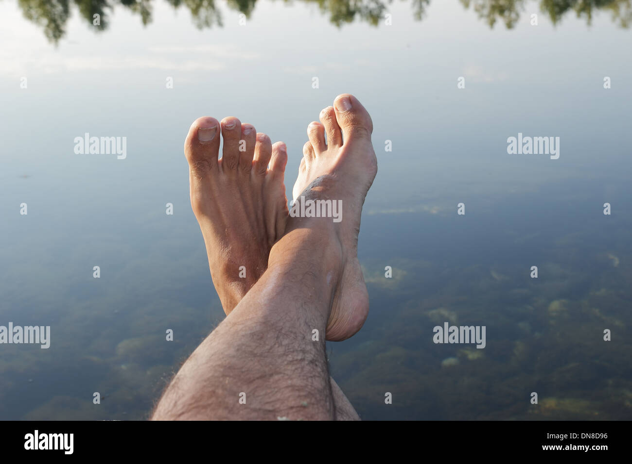 Rilassante piedi maschio su un corpo di acqua Foto Stock