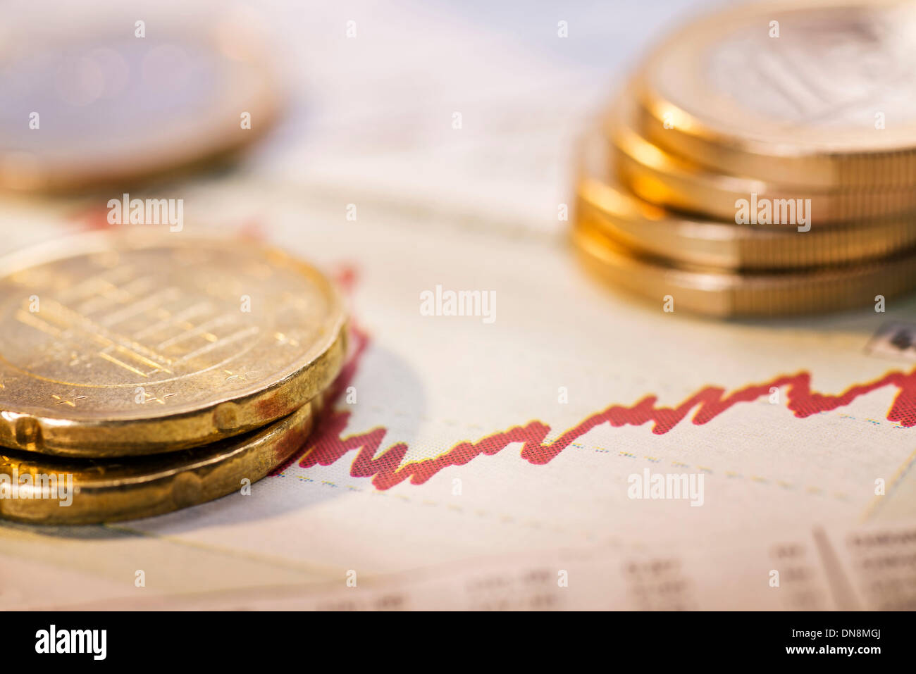 Monete metalliche in euro e un grafico con la curva rossa come un simbolo della fluttuazione dei tassi di cambio. Foto Stock
