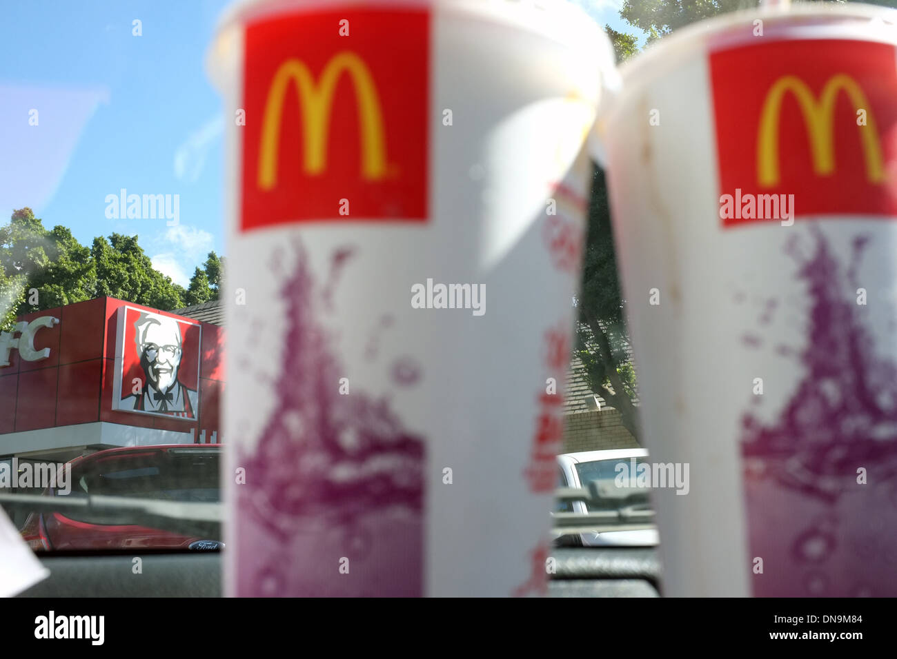 McDonalds loghi per contenitori di bevande con un KFC store in background. Foto Stock