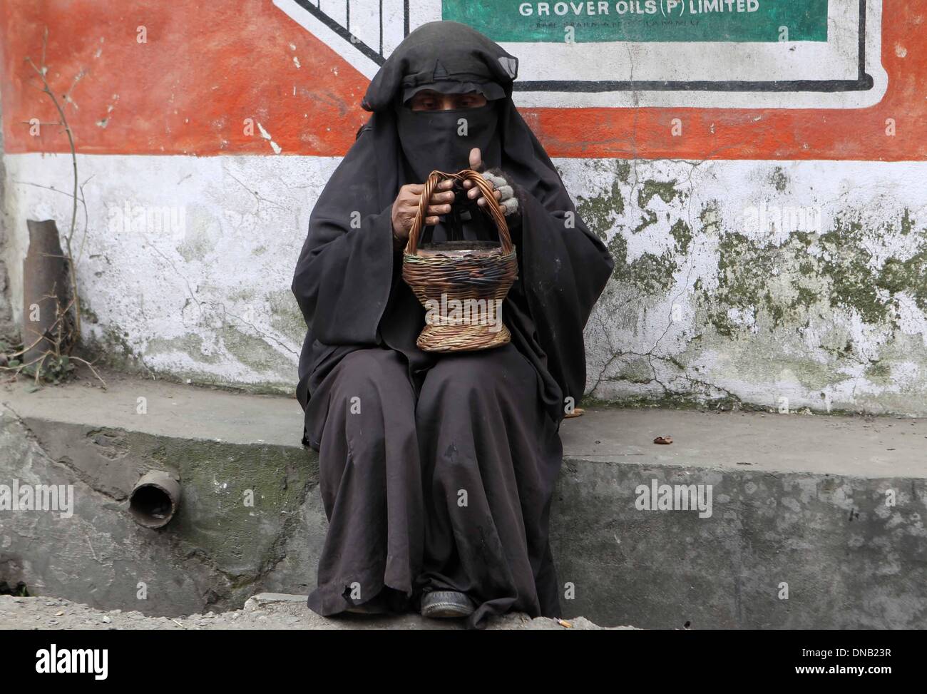 Srinagar, Indiano-controllato del Kashmir. Xxi Dec, 2013. Una donna del Kashmir scalda le mani su un tradizionale fire-pot, o Kangri, in un freddo giorno di Srinagar, capitale estiva di Indiano-Kashmir controllata, 21 dicembre 2013. Il 40-giorno periodo più dure di inverno nella valle del Kashmir, noto come 'Chillai-Kalan', inizia il sabato con una fredda mattina. Credito: Javed Dar/Xinhua/Alamy Live News Foto Stock