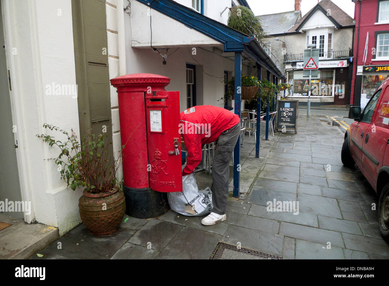 Ufficio postale di riempimento del lavoratore il suo sacco di posta da un pilastro rosso post box in Llandovery Carmarthenshire Wales UK KATHY DEWITT Foto Stock