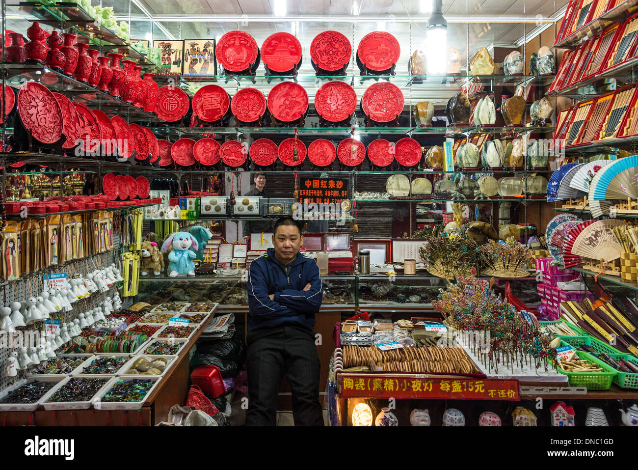 Un negozio keeper presso un negozio di souvenir. Nanjing, Jiansu Provincia, Cina. Foto Stock