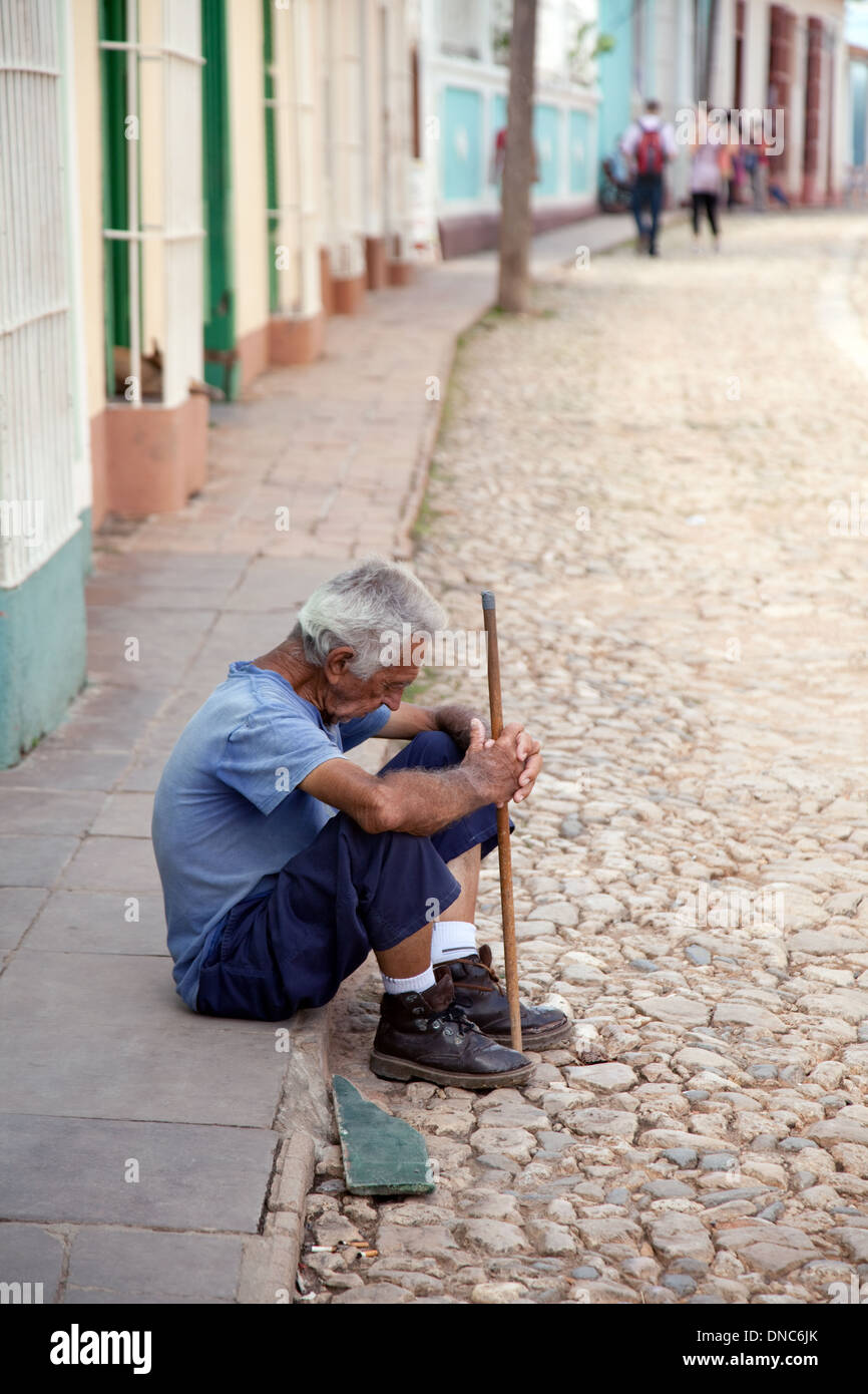Povero vecchio uomo seduto in strada, esempio di povertà in Trinidad, Cuba Caraibi, America Latina Foto Stock