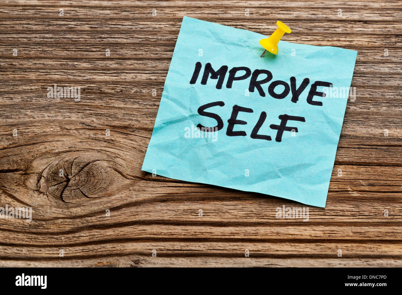 Migliorare self motivazionali di promemoria su un foglietto adesivo contro il legno zigrinato Foto Stock