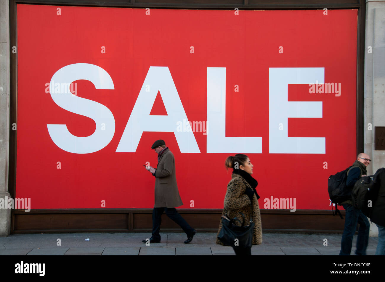Londra. Natale 2013. shopping. vendite . La gente passa di fronte a un gigante vendita sign in una vetrina su Regent street Foto Stock