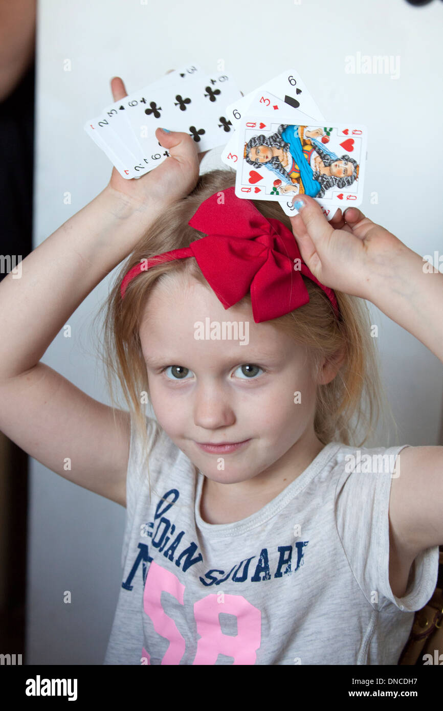 Ragazza 6 anni azienda carte da gioco sulla sua testa. Lodz Polonia centrale Foto Stock