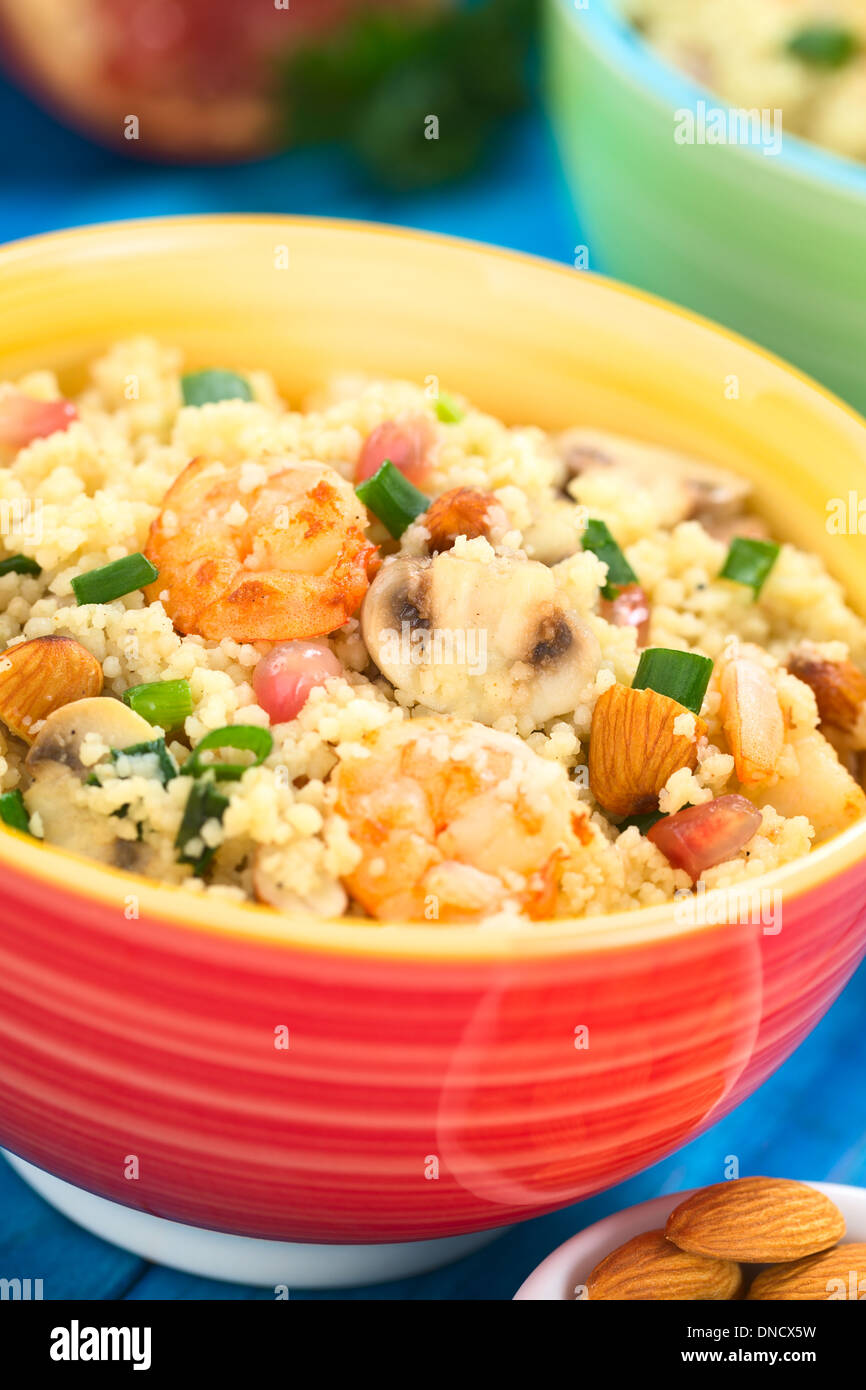 Il cous cous piatto con gamberetti, fungo, mandorla, i semi di melograno e cipolla verde servito in tazza colorata Foto Stock