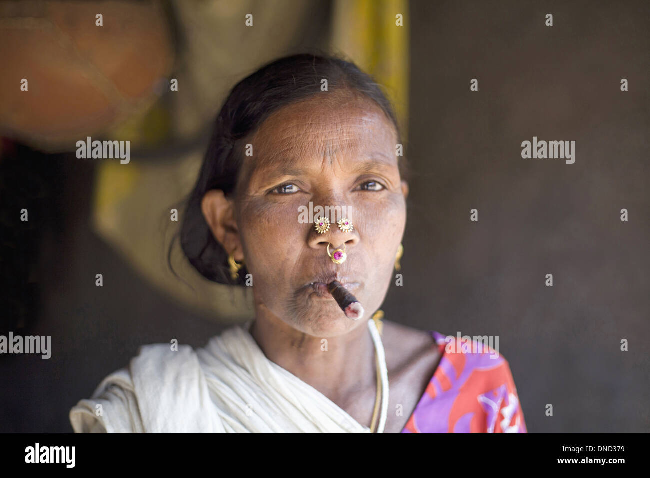 Primo piano di una vecchia donna tribale che fuma bidi, una sigaretta indiana fatta a mano di tabacco o foglie di beedi, Orissa, India. Facce rurali dell'India Foto Stock