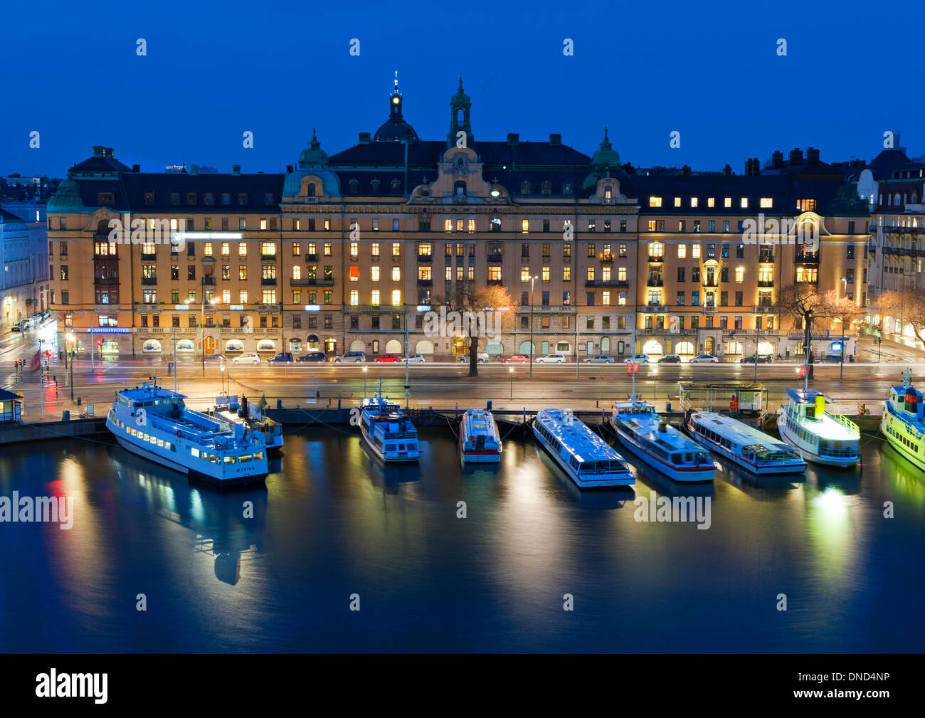 Piccoli traghetti ormeggiati a Nybroviken bay, con l'edificio Art Nouveau, 1-5 Strandvägen (1902-1904) sul boulevard dietro. Foto Stock